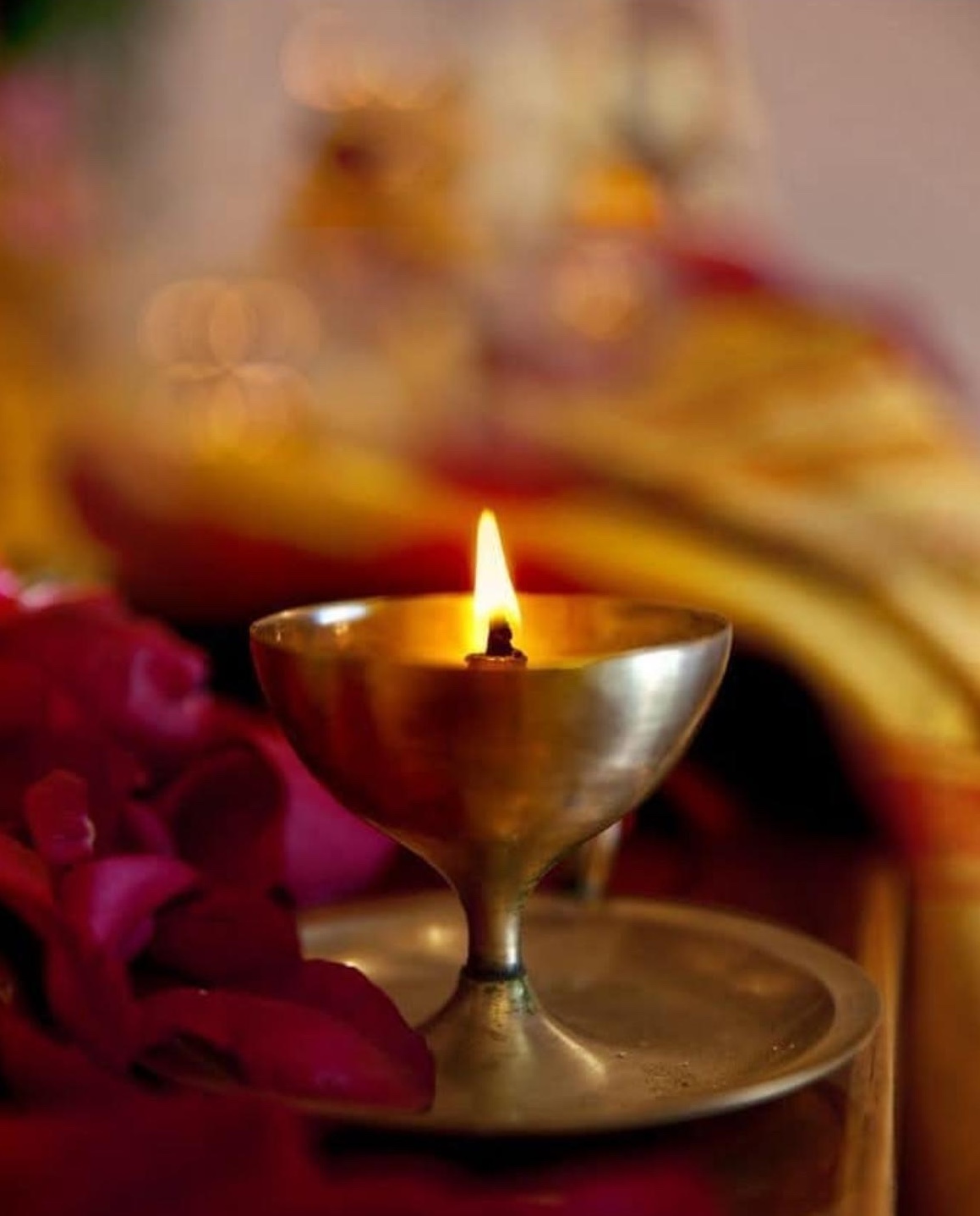 A lit diya amid rose petals